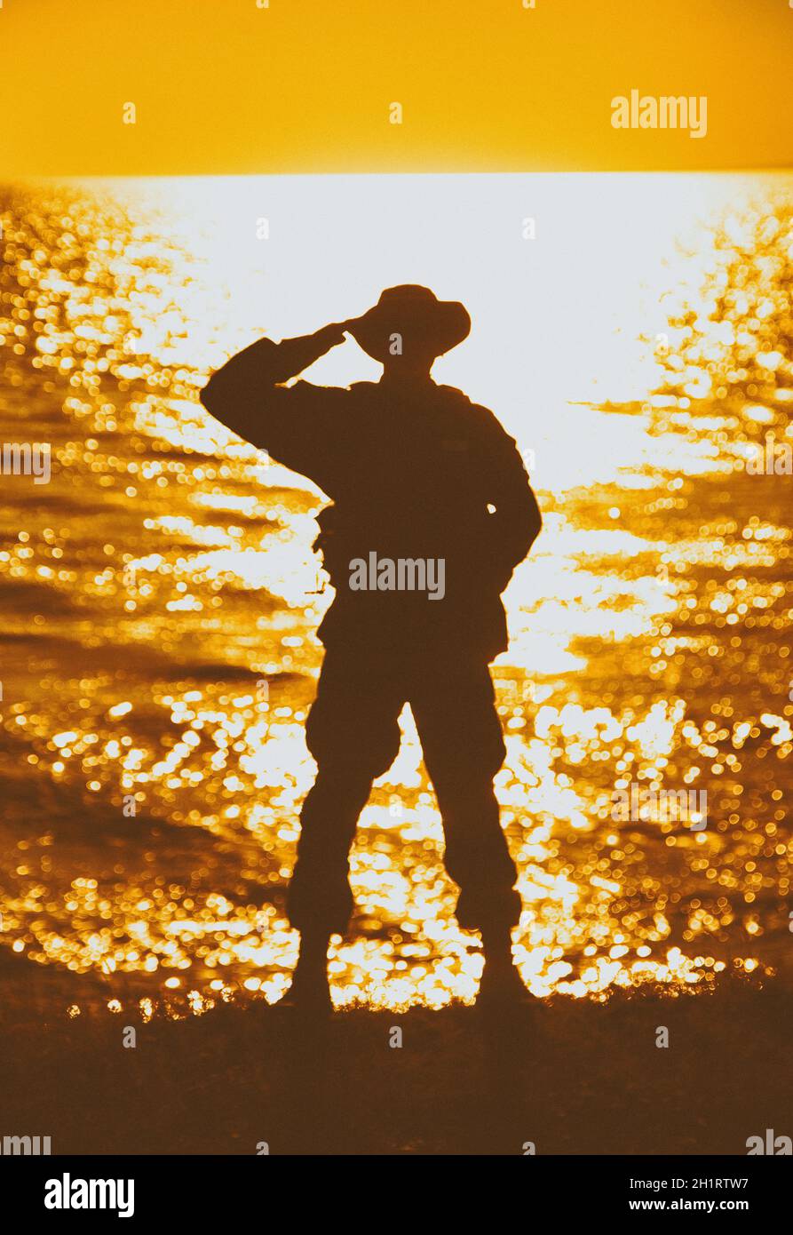 Silhouette de soldat commando salant, fantassin de l'armée debout sur la rive pendant le coucher du soleil ou le lever du soleil.Cérémonie solennelle militaire, hommage respectable pour Banque D'Images