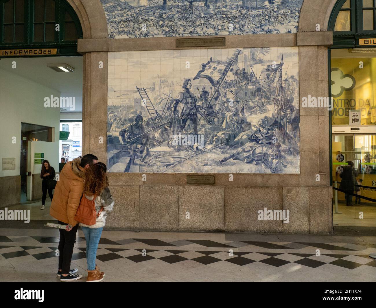 Gare de Sao Bento - couple concernant un mur avec des tuiles Azulejo montrant des scènes historiques - Porto Banque D'Images