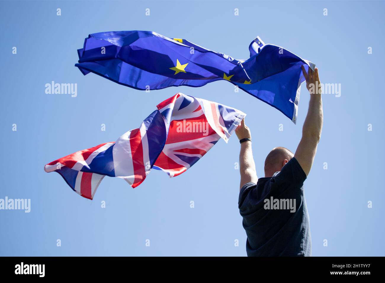Homme portant les drapeaux du Royaume-Uni et de l'Union européenne. Coalition, concept du Brexit. Banque D'Images