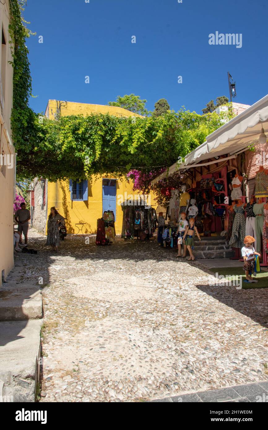 RHODES, Grèce - 07 JUIN 2021. Une petite rue de la célèbre rue Socrates dans la vieille ville de Rhodes avec une Maison jaune et une boutique de vêtements. Banque D'Images