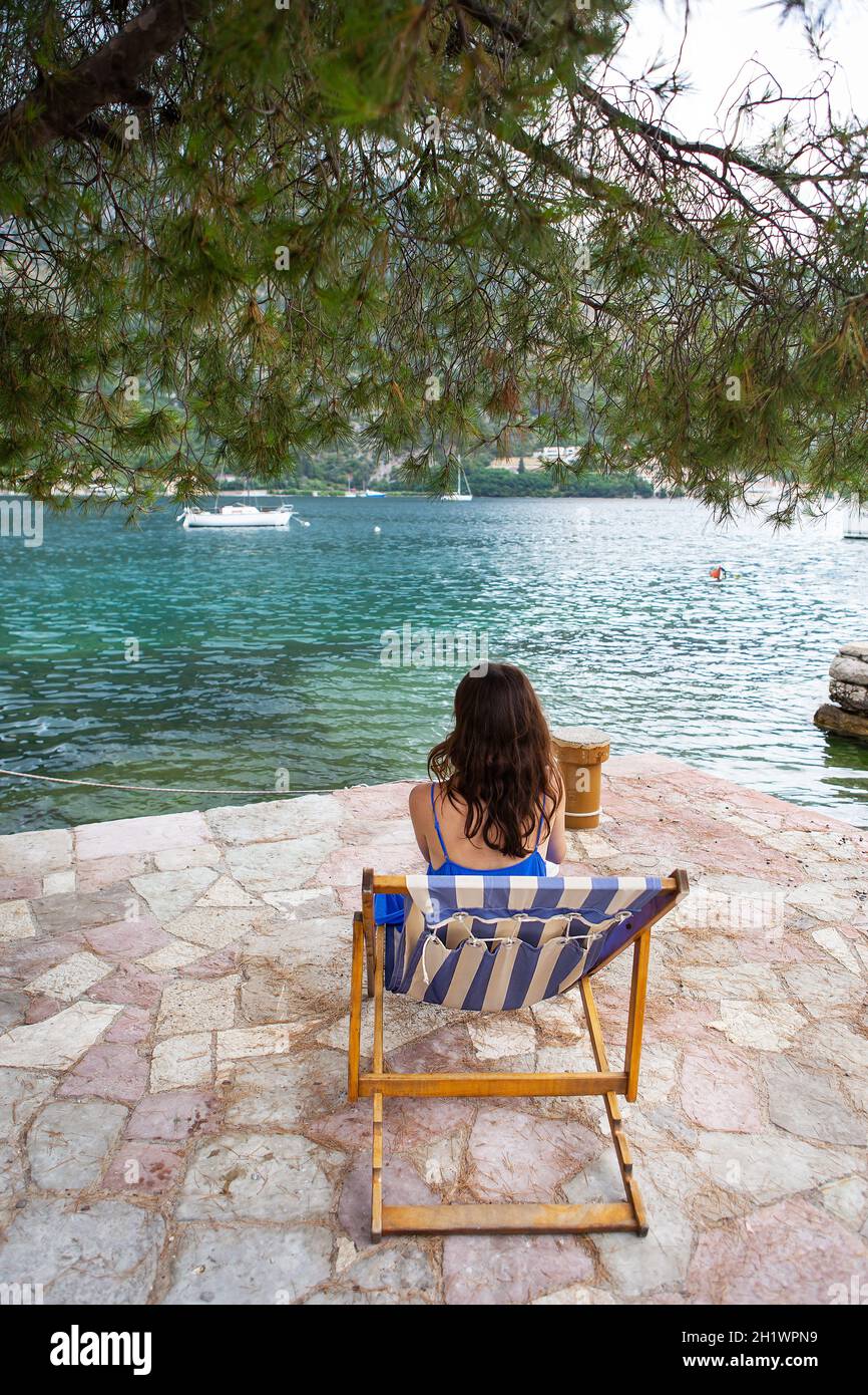 Très beau remblai de la baie de Kotor, Monténégro. La jeune fille est assise sur une chaise longue rayée. Le concept de repos et de vacances en Europe Banque D'Images