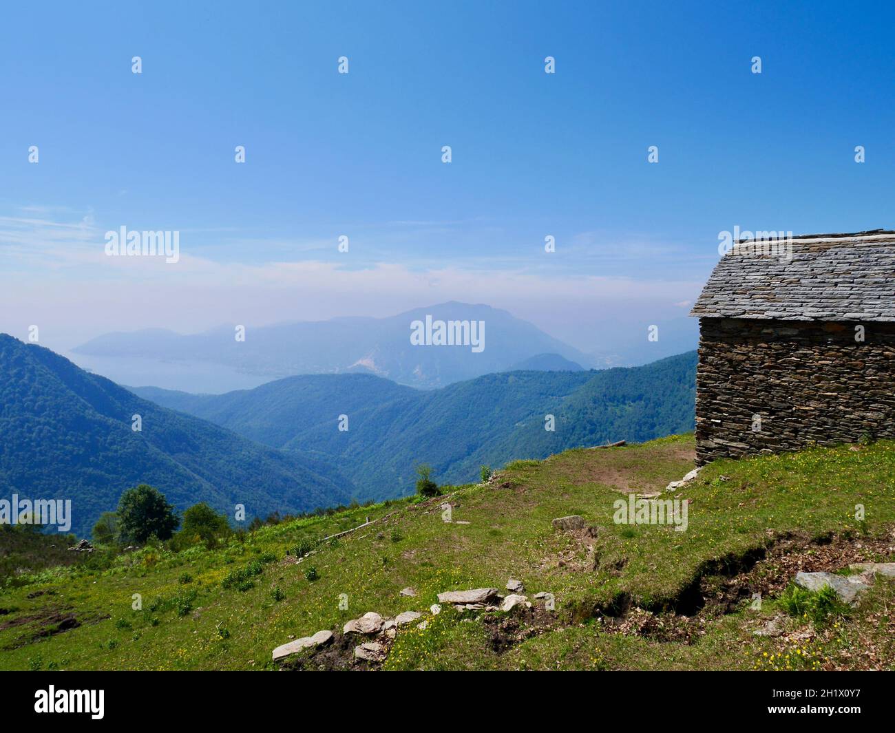 Cabane traditionnelle en pierre à Cima Sasso à Val Grande, parc national du Piémont, Italie.Vue panoramique sur le Lago Maggiore. Banque D'Images