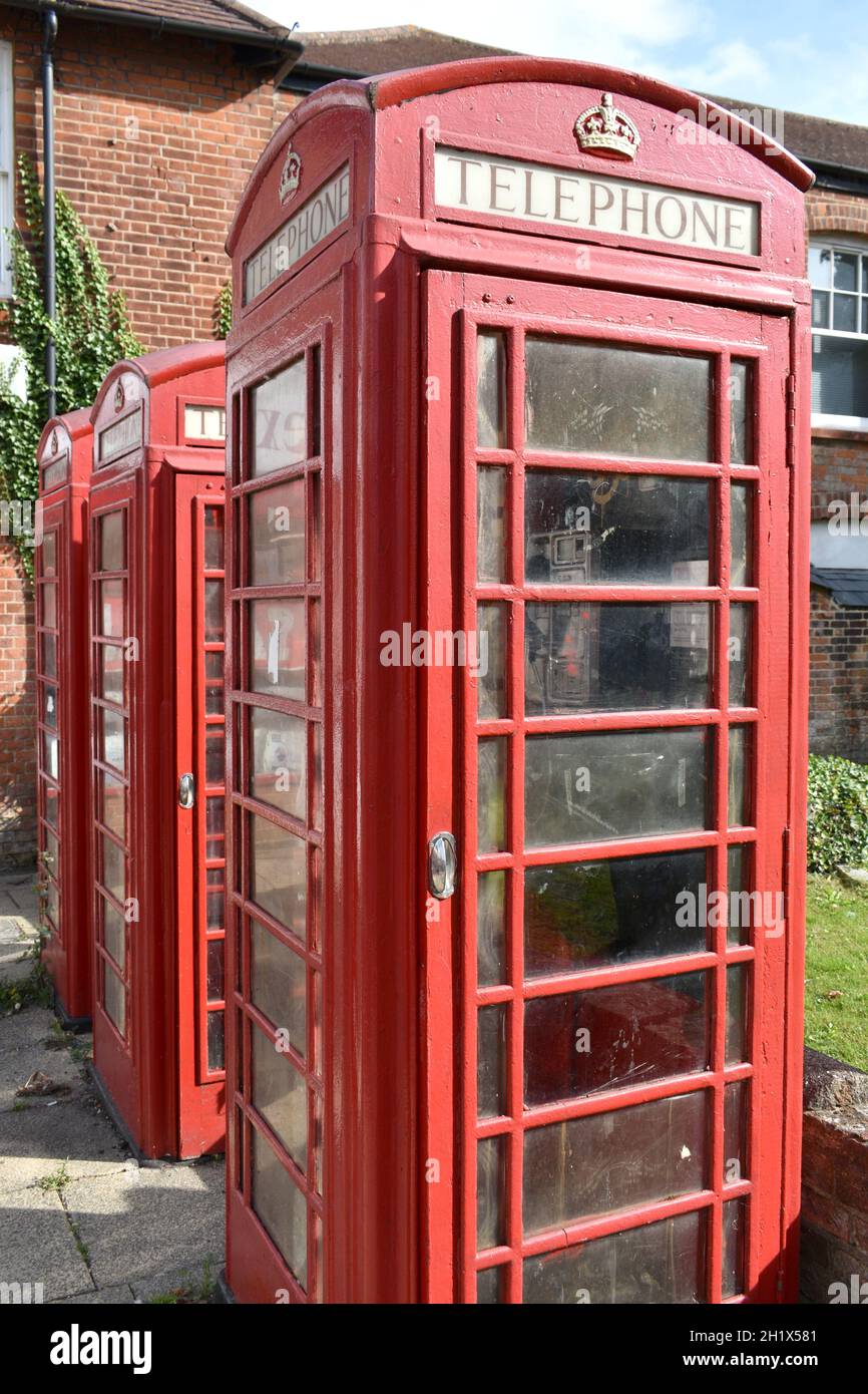 gros plan de 3 boîtes téléphoniques rouges vintage avec couronne royale d'or sur le dessus, dans une rue à l'extérieur d'un bâtiment en brique en été Banque D'Images