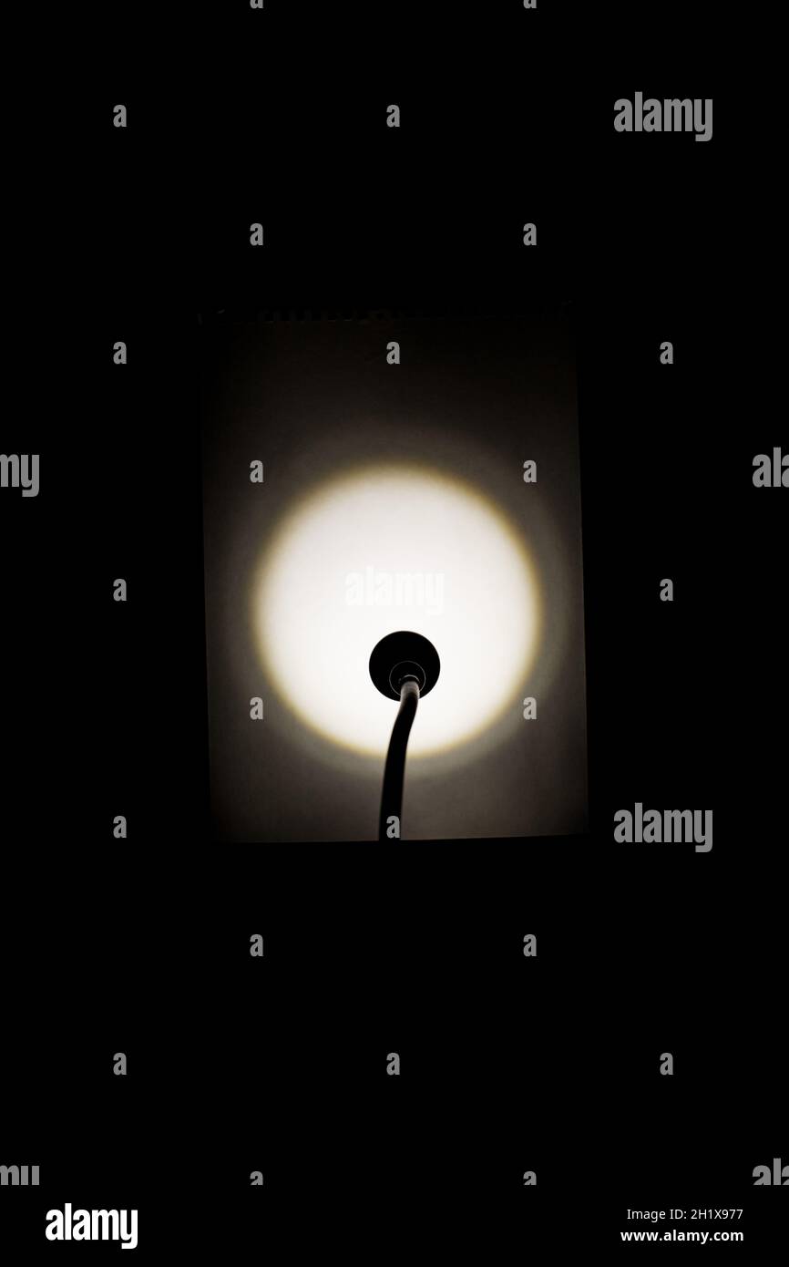La lumière d'une lampe de table éclaire une feuille de papier blanche. Banque D'Images