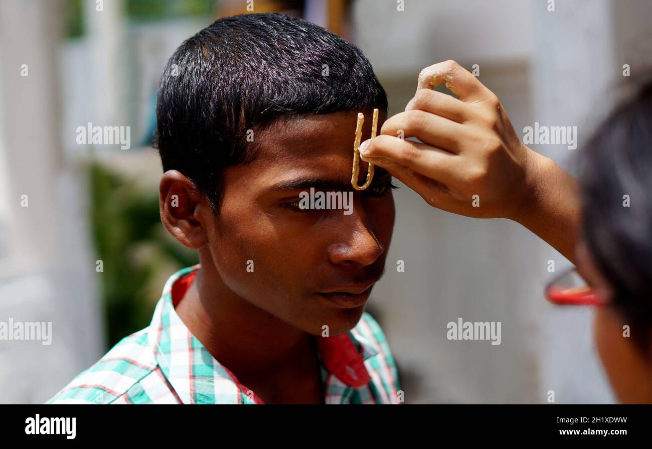 HYDERABAD,INDE-AOÛT 24,2019: La femme hindoue indienne applique Tilak sur la tête avant, un rituel religieux, sur la célébration du festival Krisnastami dans Dieu Krishna temp Banque D'Images