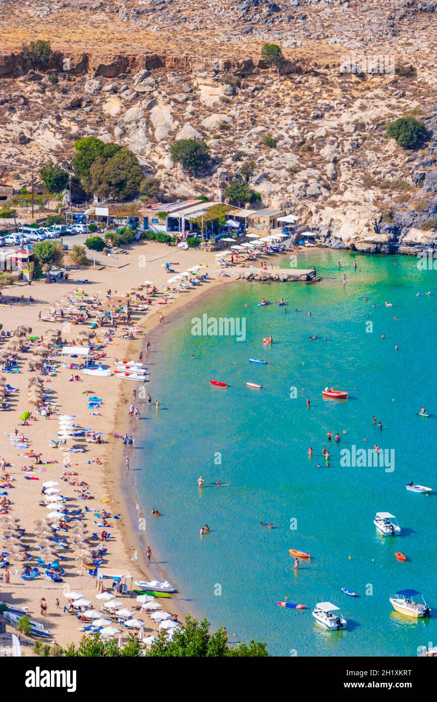 Vue panoramique sur la baie de Lindos Beach avec bateaux d'eau turquoise touristes et soleil sur Rhodes Grèce. Banque D'Images