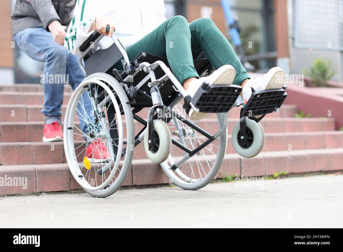 Un homme lève les marches en fauteuil roulant avec une femme en gros plan Banque D'Images