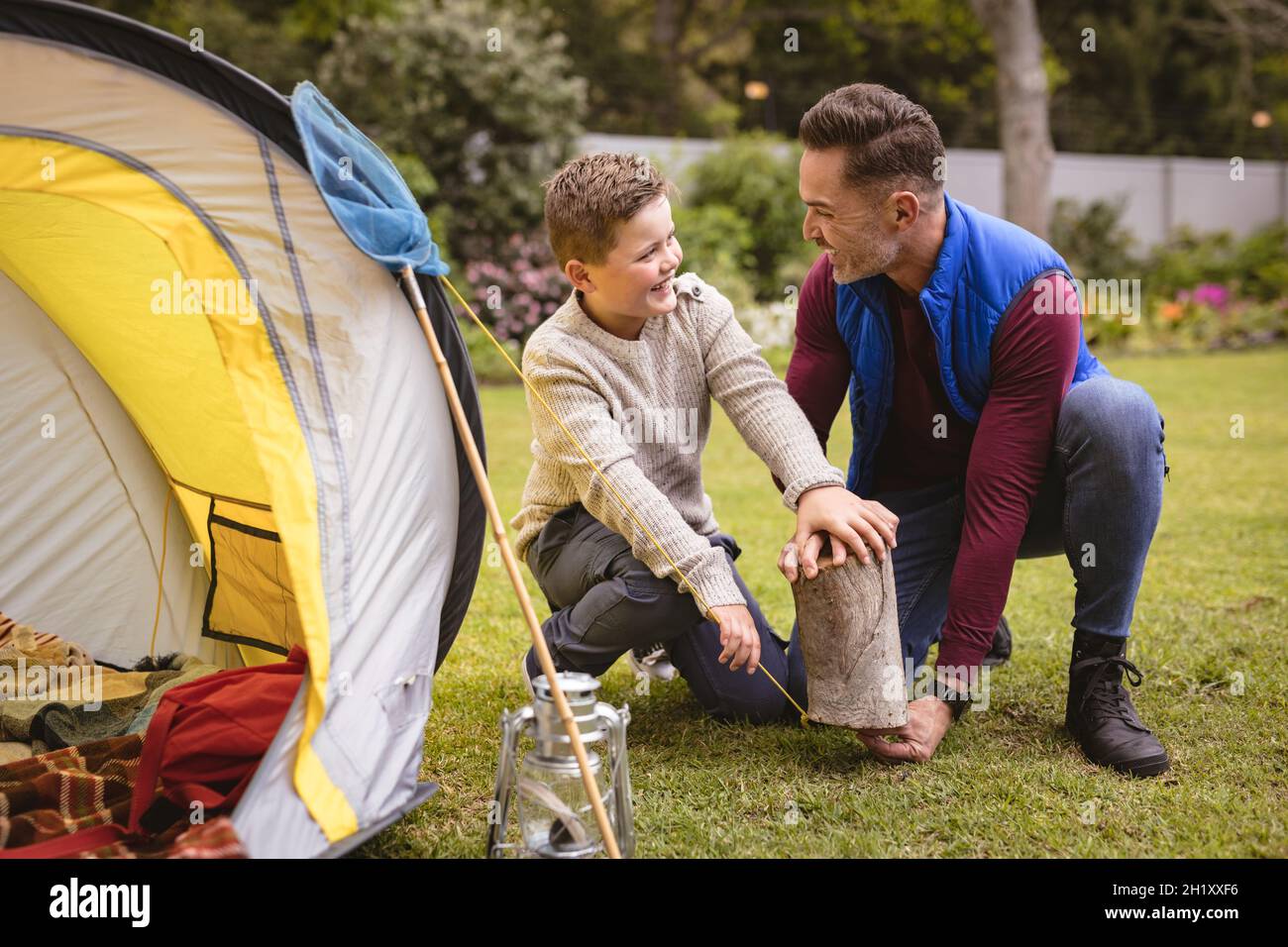 Un père et un fils caucasiens souriant tout en dressant une tente ensemble dans le jardin Banque D'Images