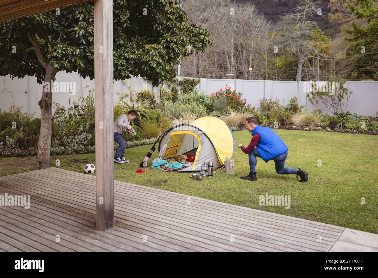 Un père et un fils caucasiens souriant tout en dressant une tente ensemble dans le jardin Banque D'Images