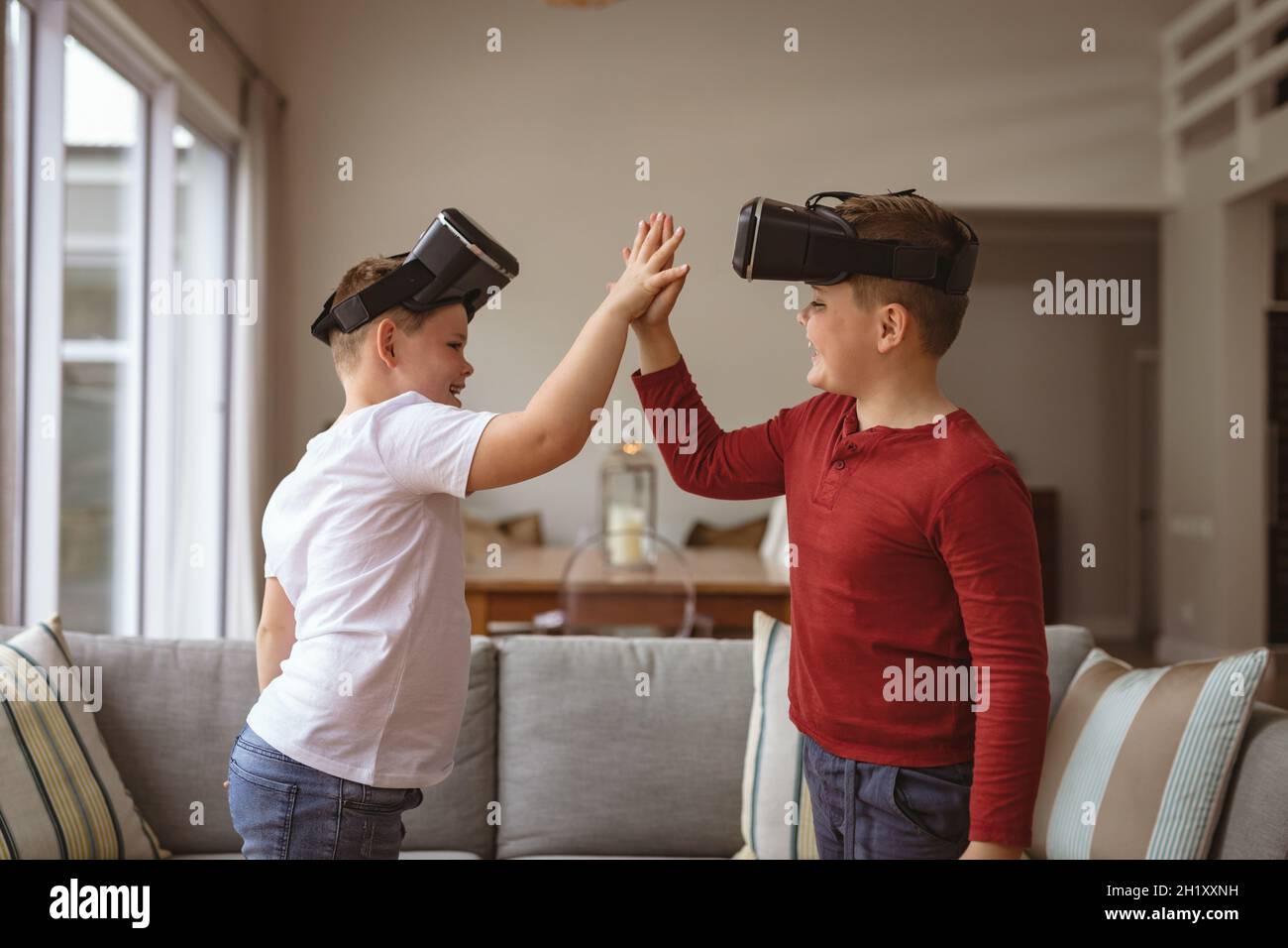 Deux garçons de race blanche portant des micro-casques vr se portant les uns sur les autres à la maison Banque D'Images