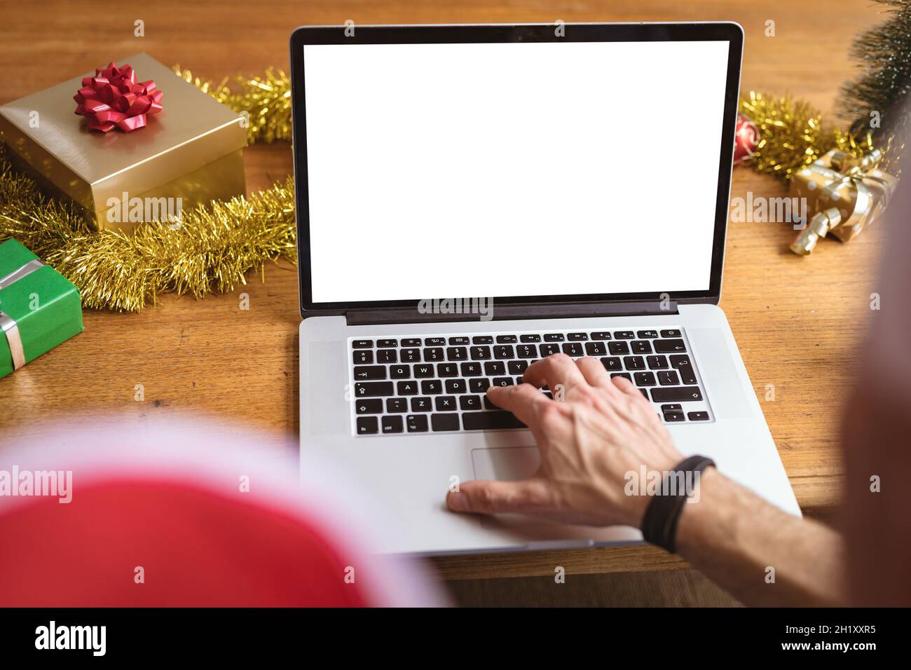 Mi-section de l'homme portant un chapeau de père noël utilisant un ordinateur portable avec espace de copie à la maison pendant noël Banque D'Images