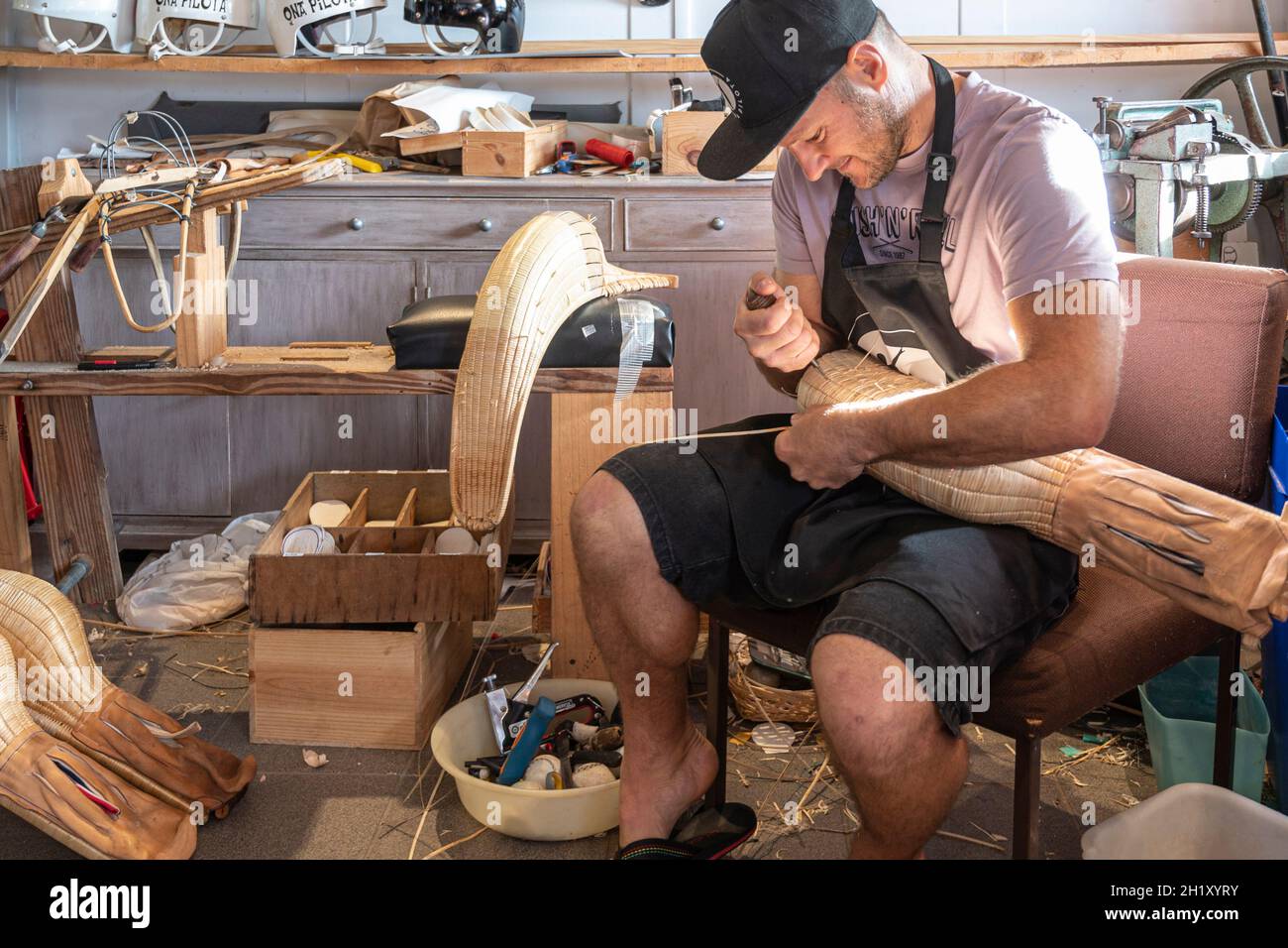L'ancien champion du monde Patxi Tambourindeguy réparse un grand chistera dans son atelier de pelota à Bidart, France Banque D'Images