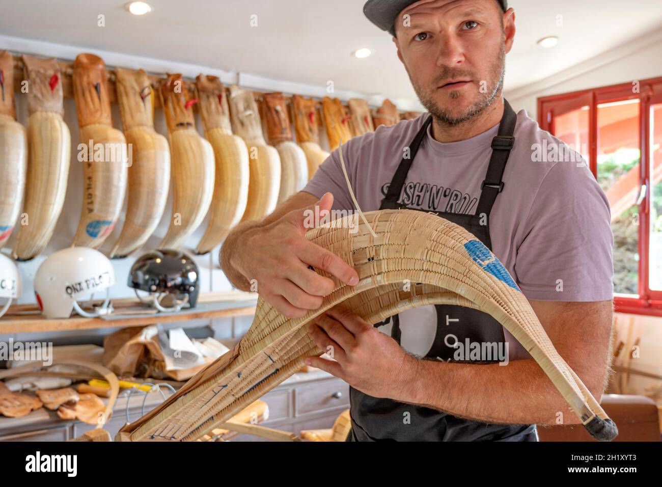 L'ancien champion du monde Patxi Tambourindeguy réparse un grand chistera dans son atelier de pelota à Bidart, France Banque D'Images