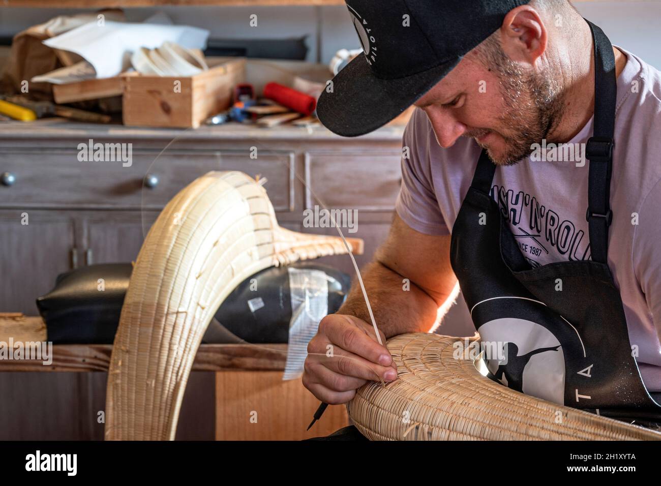 L'ancien champion du monde Patxi Tambourindeguy réparse un grand chistera dans son atelier de pelota à Bidart, France Banque D'Images