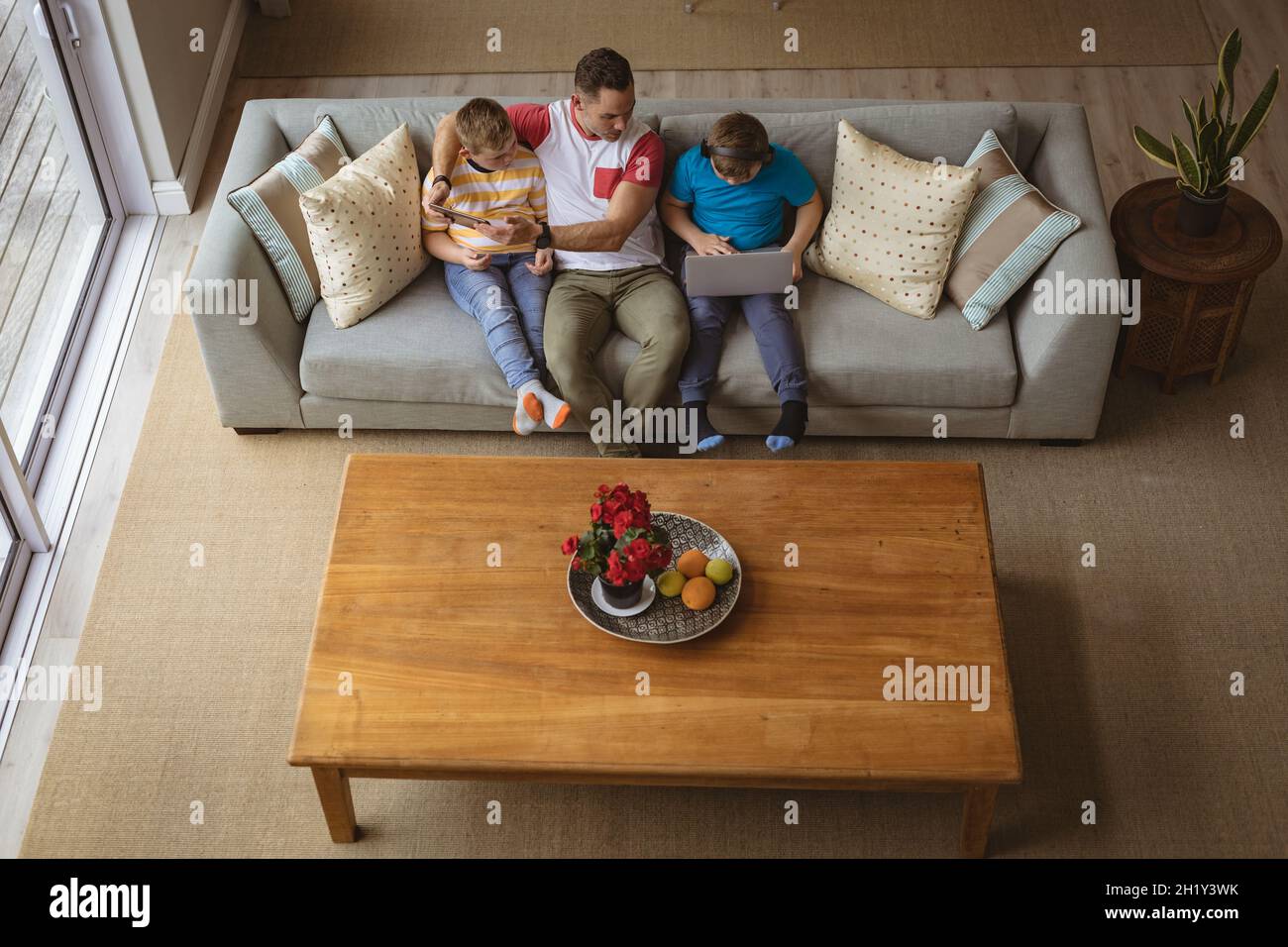Vue en hauteur du père caucasien et de deux fils utilisant un ordinateur portable et une tablette numérique à la maison Banque D'Images