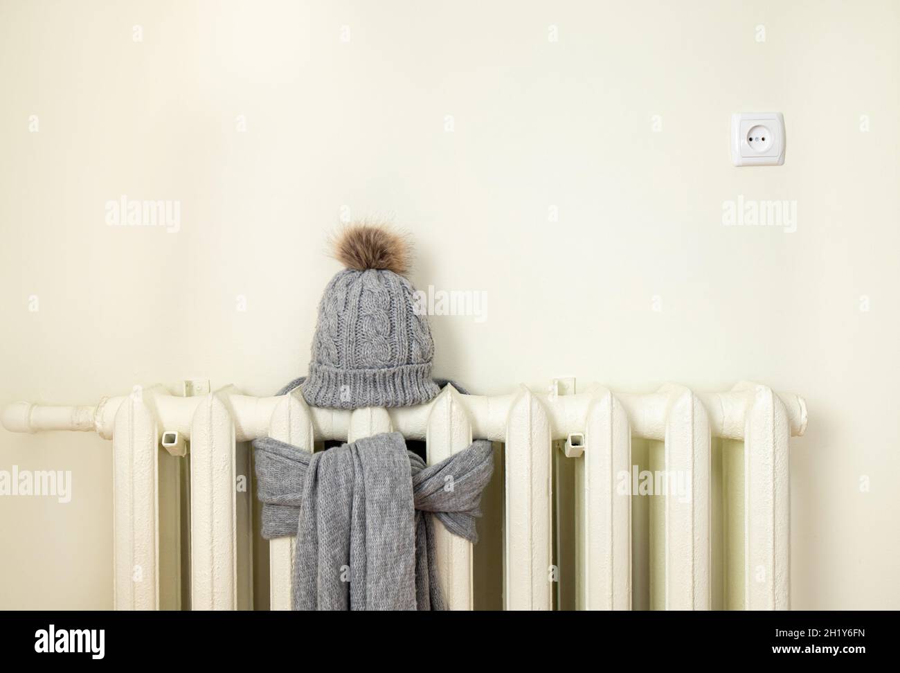 Radiateur de chauffage vintage avec bonnet d'hiver tricoté en laine et écharpe.La facture d'électricité et de gaz monte, concept européen de crise énergétique. Banque D'Images
