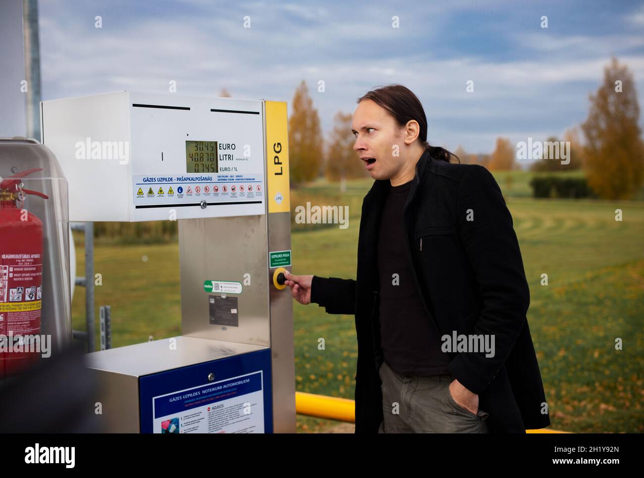 Un beau homme surpris à la station-service GPL regarde à la hausse le prix Banque D'Images