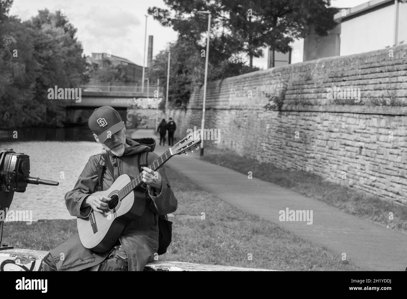 Près du chemin de halage et du canal de Leeds et Liverpool à Leeds, un homme âgé avec une barbe grise joua de la guitare acoustique, West Yorkshire, Angleterre, Royaume-Uni. Banque D'Images