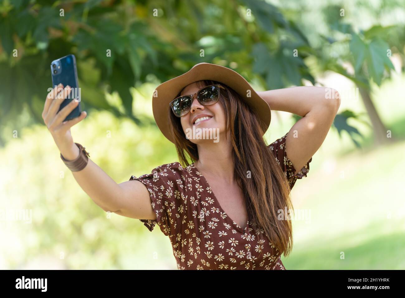 Femme prenant un selfie avec son téléphone portable avec un fond de nature floue Banque D'Images