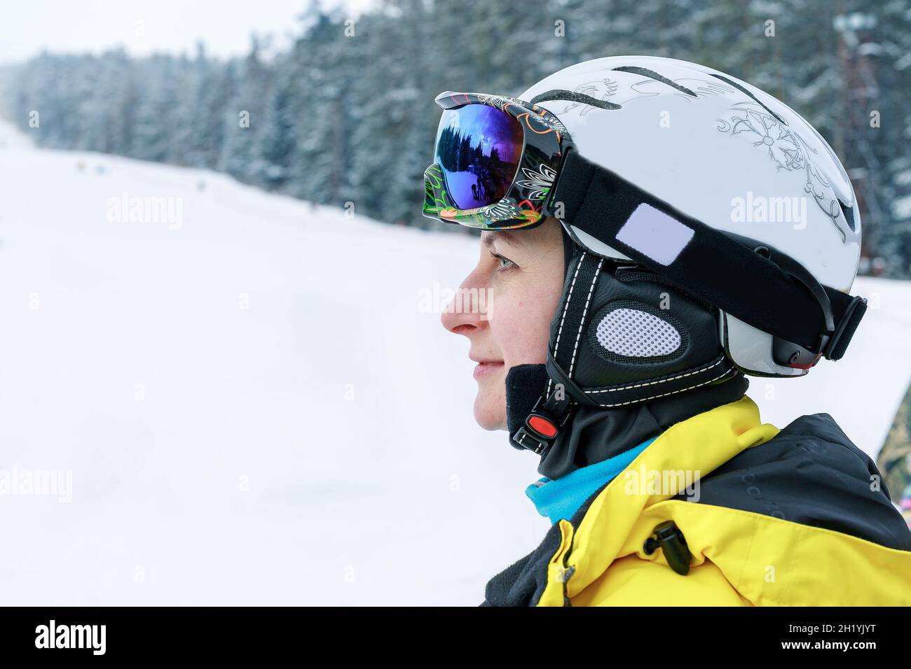 Portrait d'une jeune belle femme de race blanche dans un casque de ski et des lunettes sur le fond de la piste de ski.Vêtements de couleurs vives pour la vie active Banque D'Images