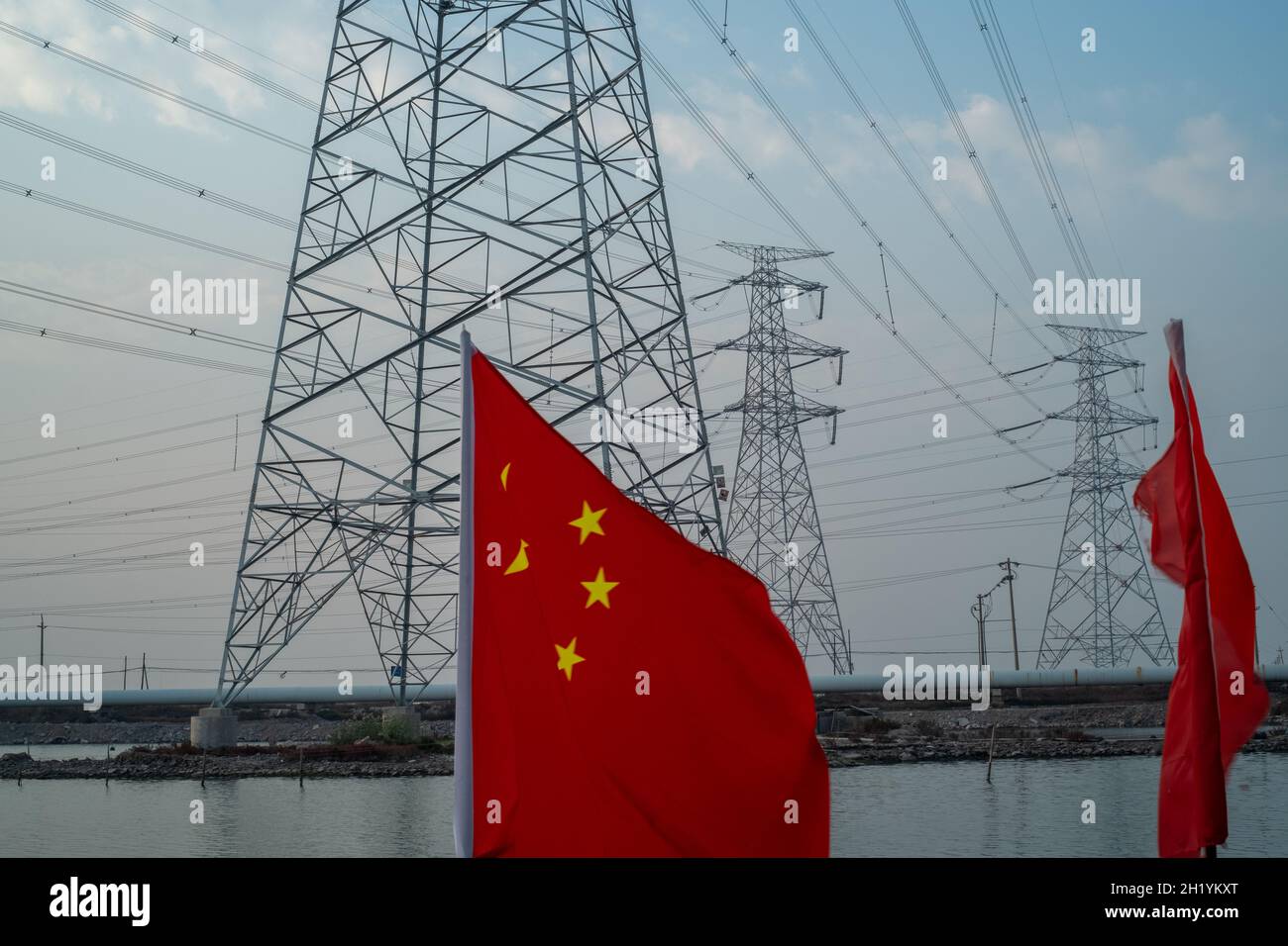 Drapeau chinois agitant devant les tours de transmission haute tension à Tianjin, en Chine.19 octobre 2021 Banque D'Images