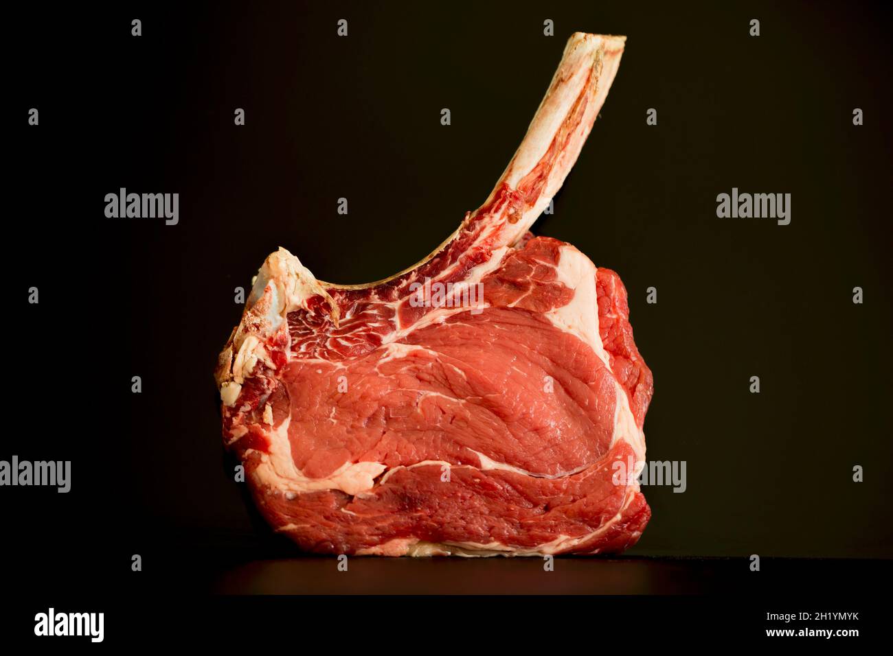 Steak de faux-filet avec un os long sur une surface sombre Banque D'Images Steak de faux-filet avec un os long sur une surface sombre Banque D'Images