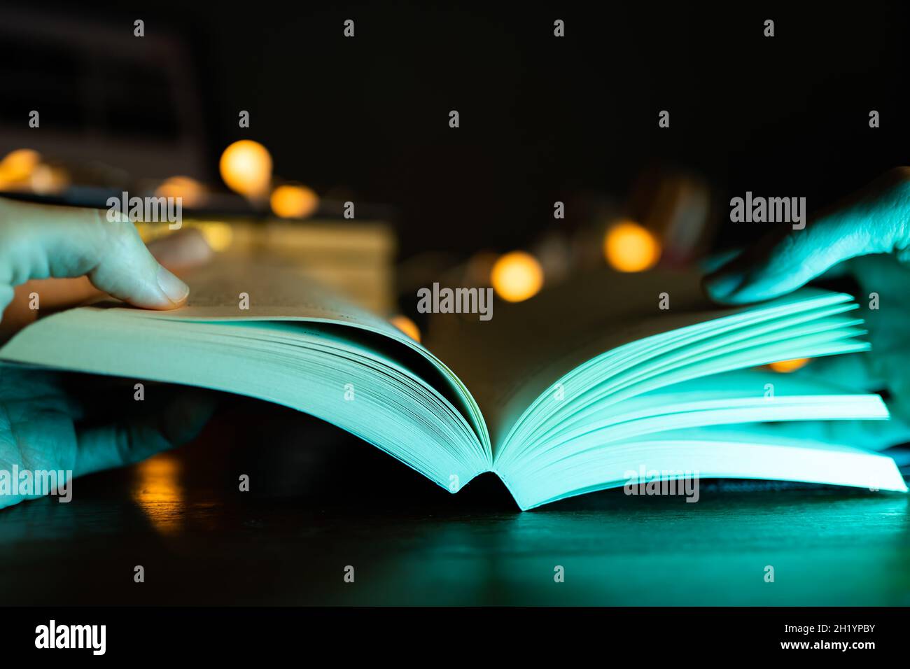 Lire un livre dans l'obscurité avec une lumière colorée Banque D'Images