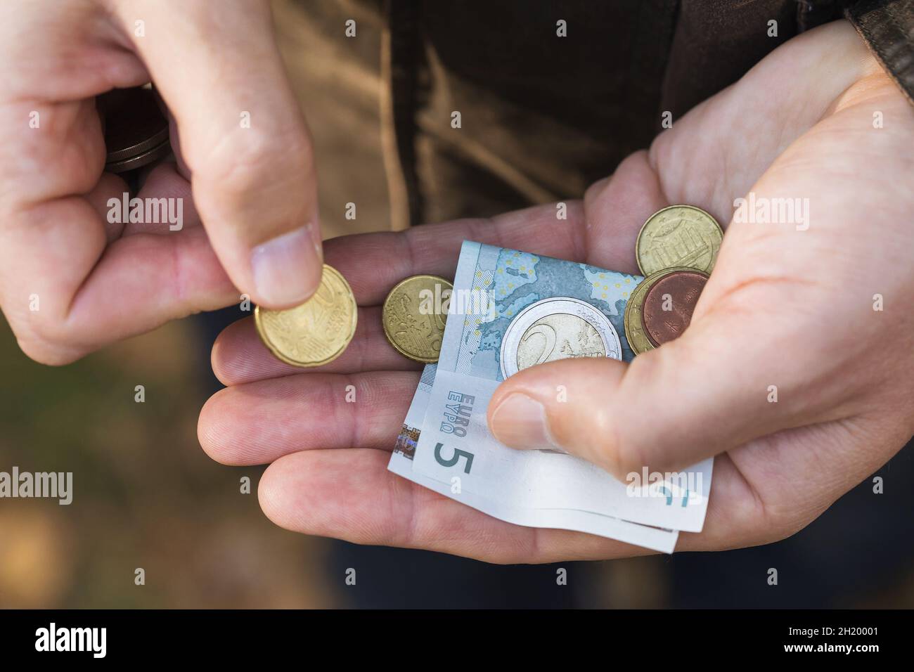 Un homme comptant des centimes d'euro et de petits billets dans la paume de sa main, gros plan Banque D'Images