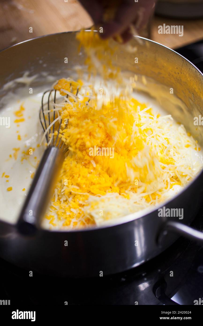 Un cuisinier prépare une sauce au fromage pour faire du fromage macaroni Banque D'Images
