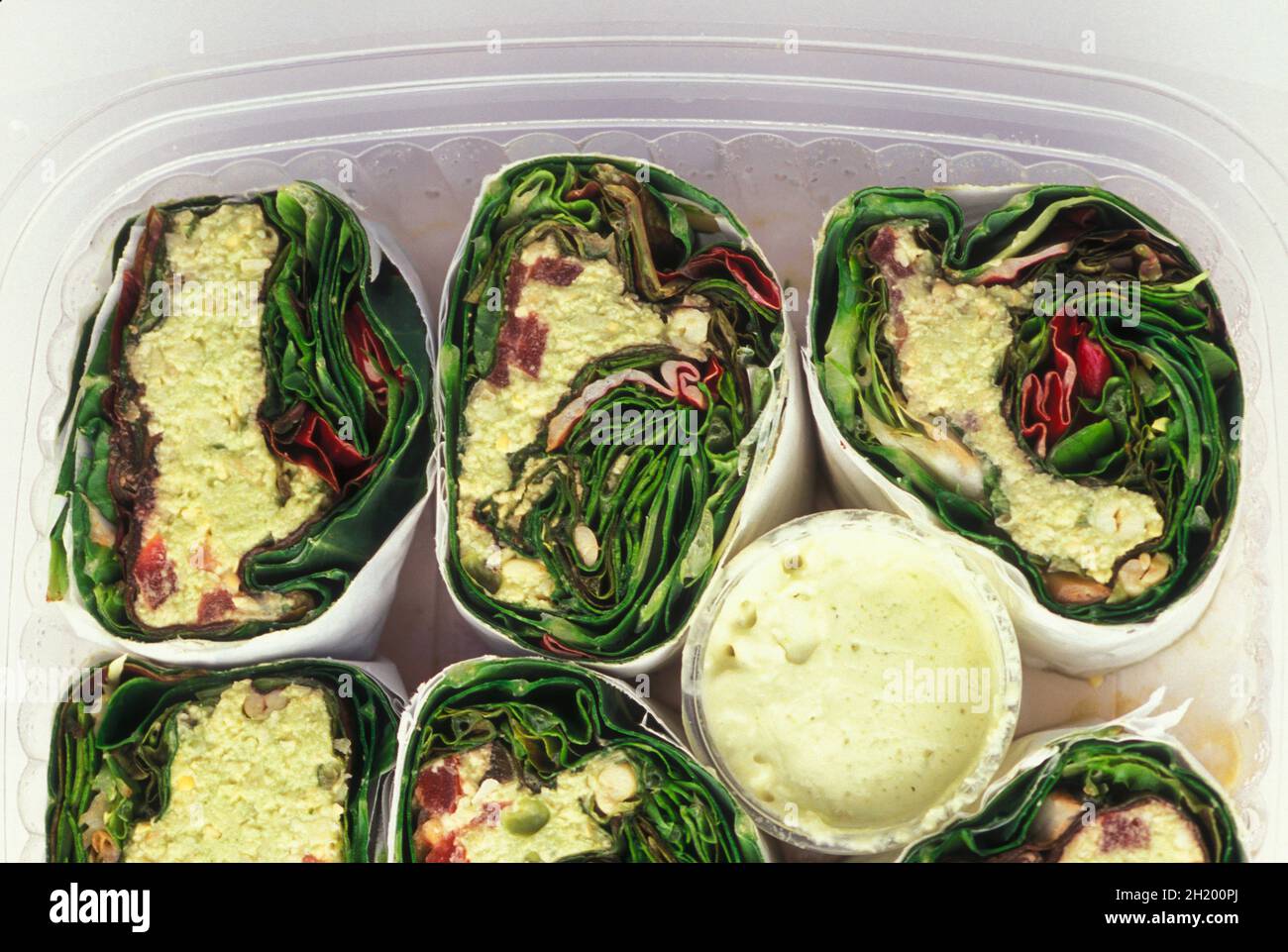 Enveloppements végétariens remplis de légumes crus dans des récipients en plastique Banque D'Images
