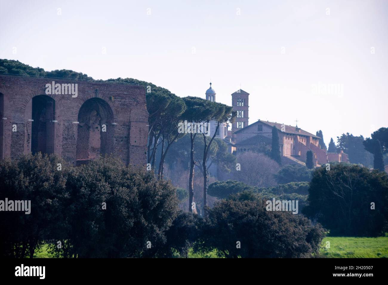 Cirque Maximus ruines à Rome près d'une église italienne campanile ou clocher et pins de pierre italiens dans la brume matinale. Banque D'Images