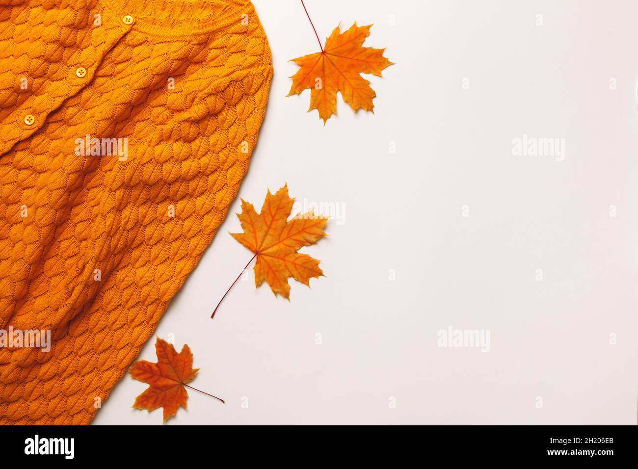 Concept d'automne.Chandail jaune-orange avec feuilles d'érable sur fond gris clair.Espace de copie de la vue de dessus de la pose à plat Banque D'Images
