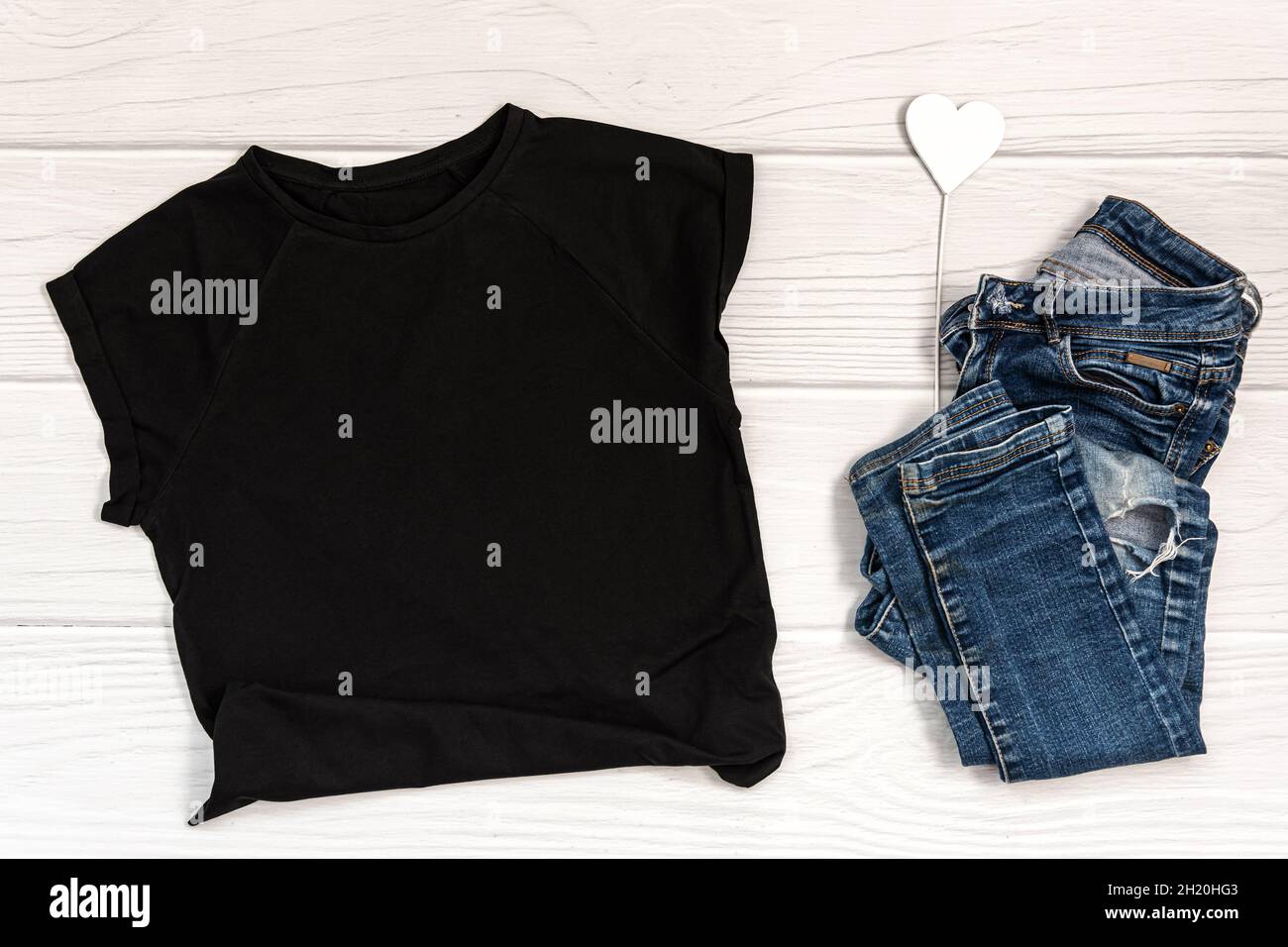 Maquette de t-shirt noir sur fond en bois blanc. Banque D'Images