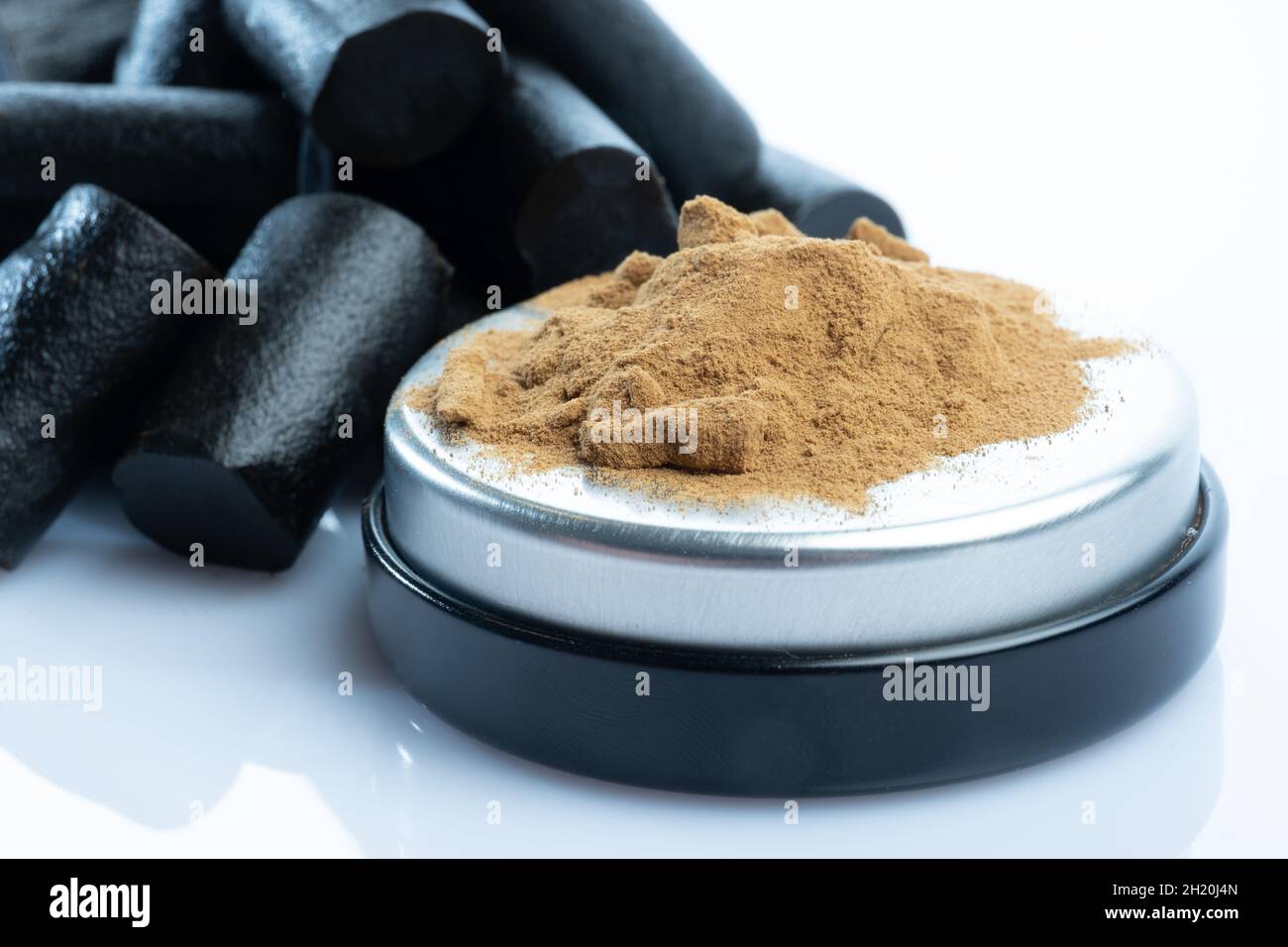 Helsinki / Finlande - 19 OCTOBRE 2021 : gros plan de la poudre de réglisse salée et d'un bouquet de réglisse finlandaise noire sur fond blanc brillant Banque D'Images