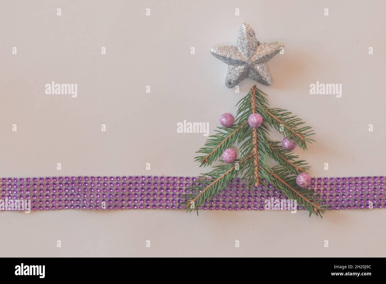 décoration d'arbre de noël vert avec boule rose et étoile argentée sur ruban violet avec espace de copie sur fond blanc Banque D'Images