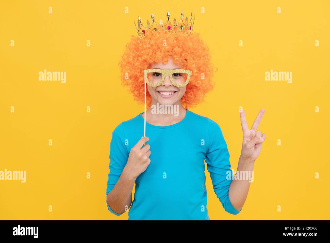 bonne fille de l'adolescence dans la fantaisie clown perruque porter la couronne de la reine et drôle de fête montre le geste de paix, amusement Banque D'Images