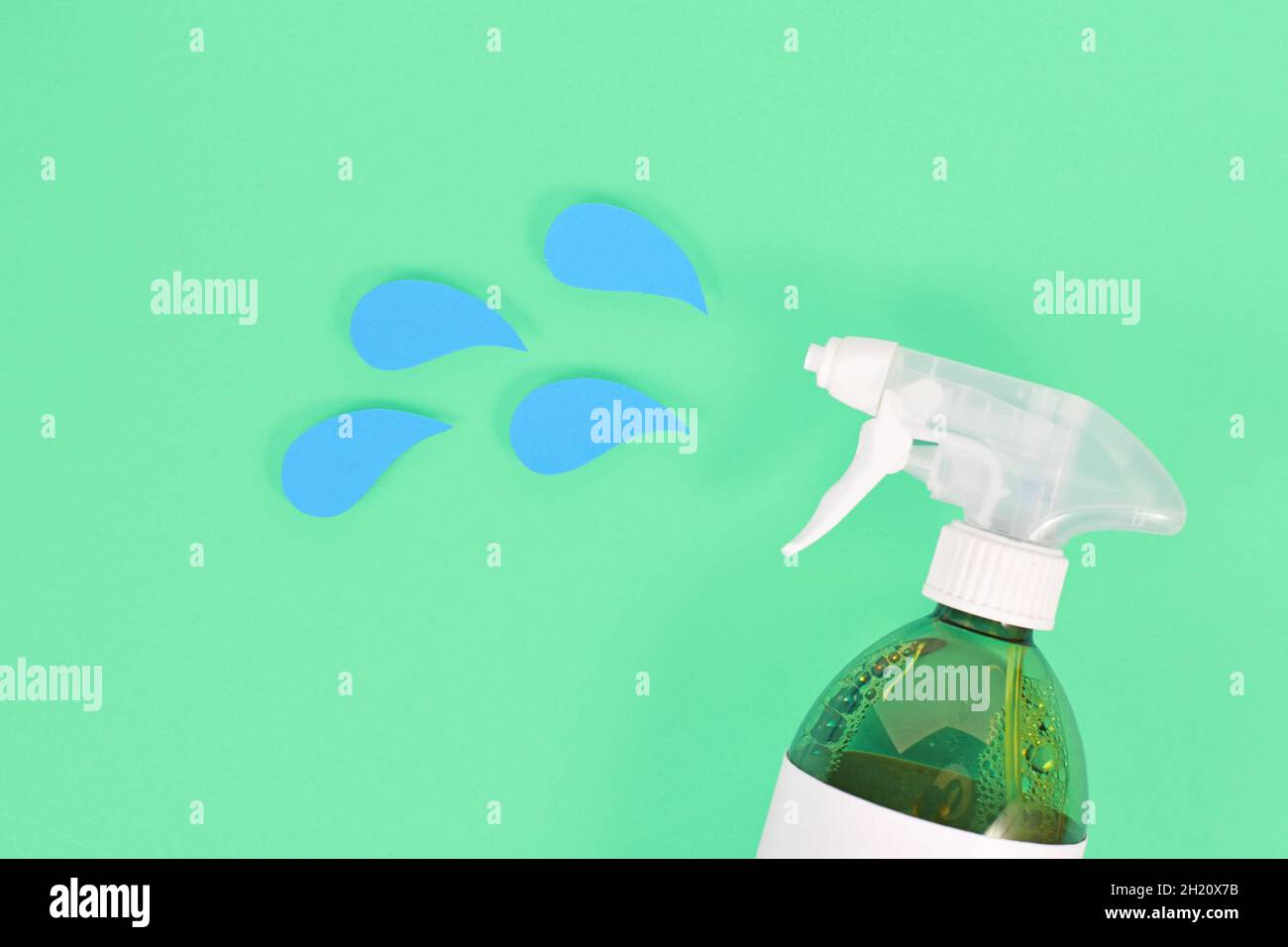 Flacon pulvérisateur d'agent nettoyant vert avec gouttes de liquide bleu coupées à partir du papier Banque D'Images