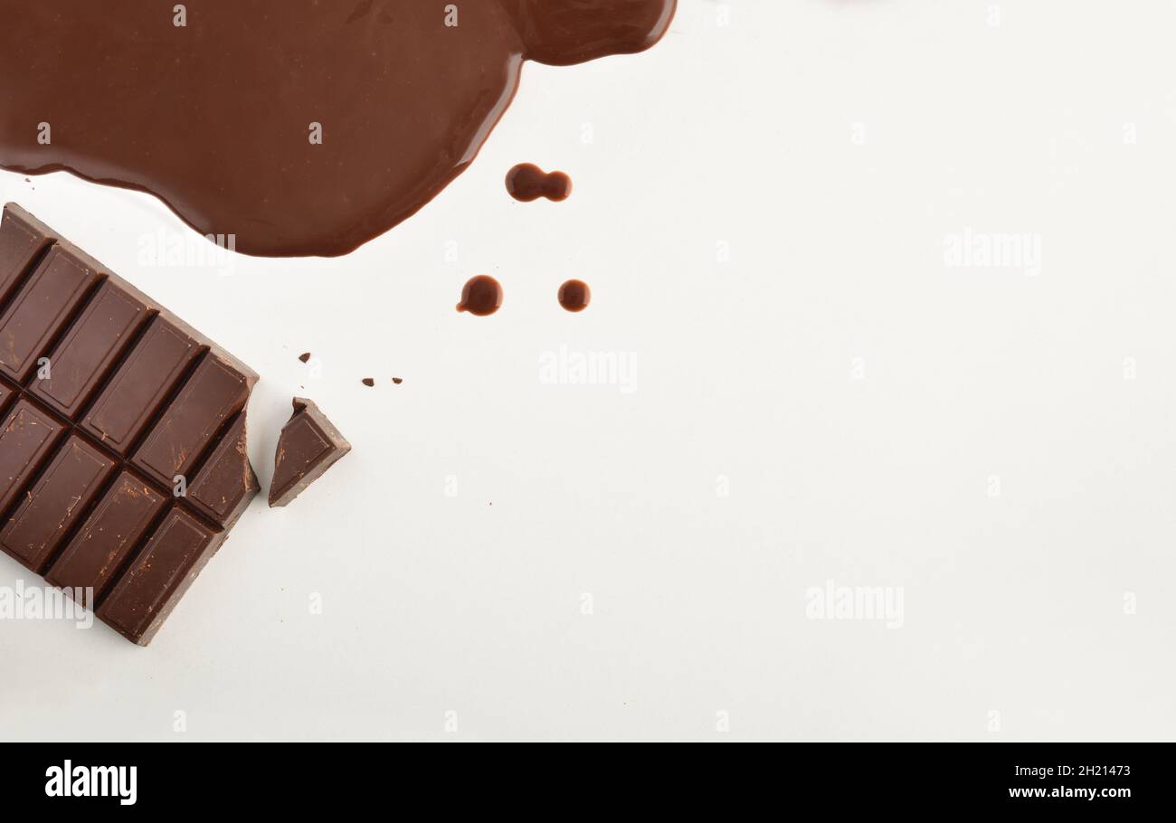 Fond avec chocolat de pâtisserie en comprimé et fondu sur une table blanche.Vue de dessus.Position horizontale. Banque D'Images