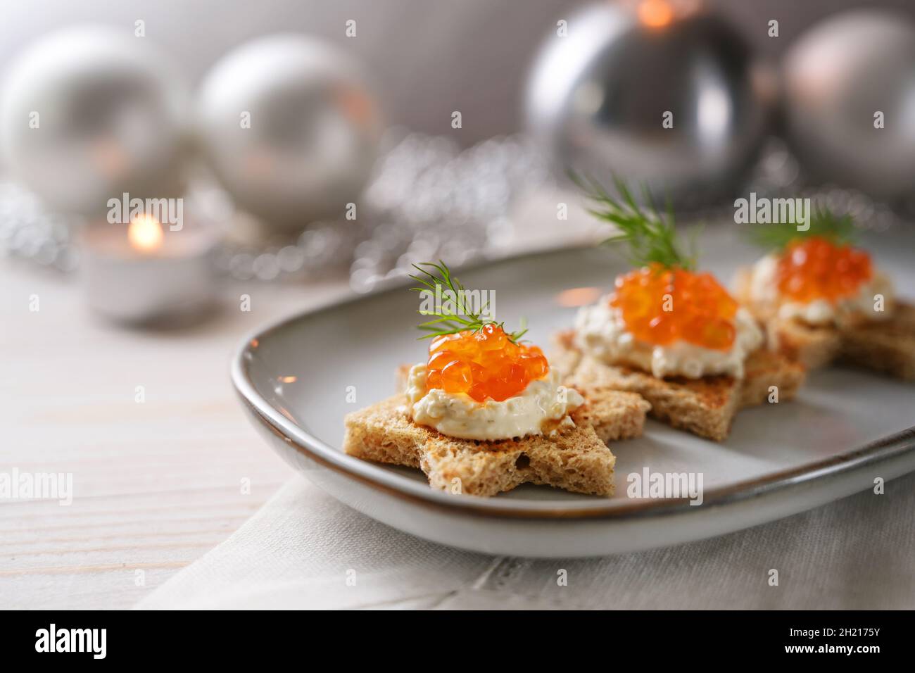 Canapés de vacances avec caviar rouge, crème et aneth sur pain grillé en forme d'étoile sur une assiette grise, décoration de Noël argentée festive, copie de spac Banque D'Images