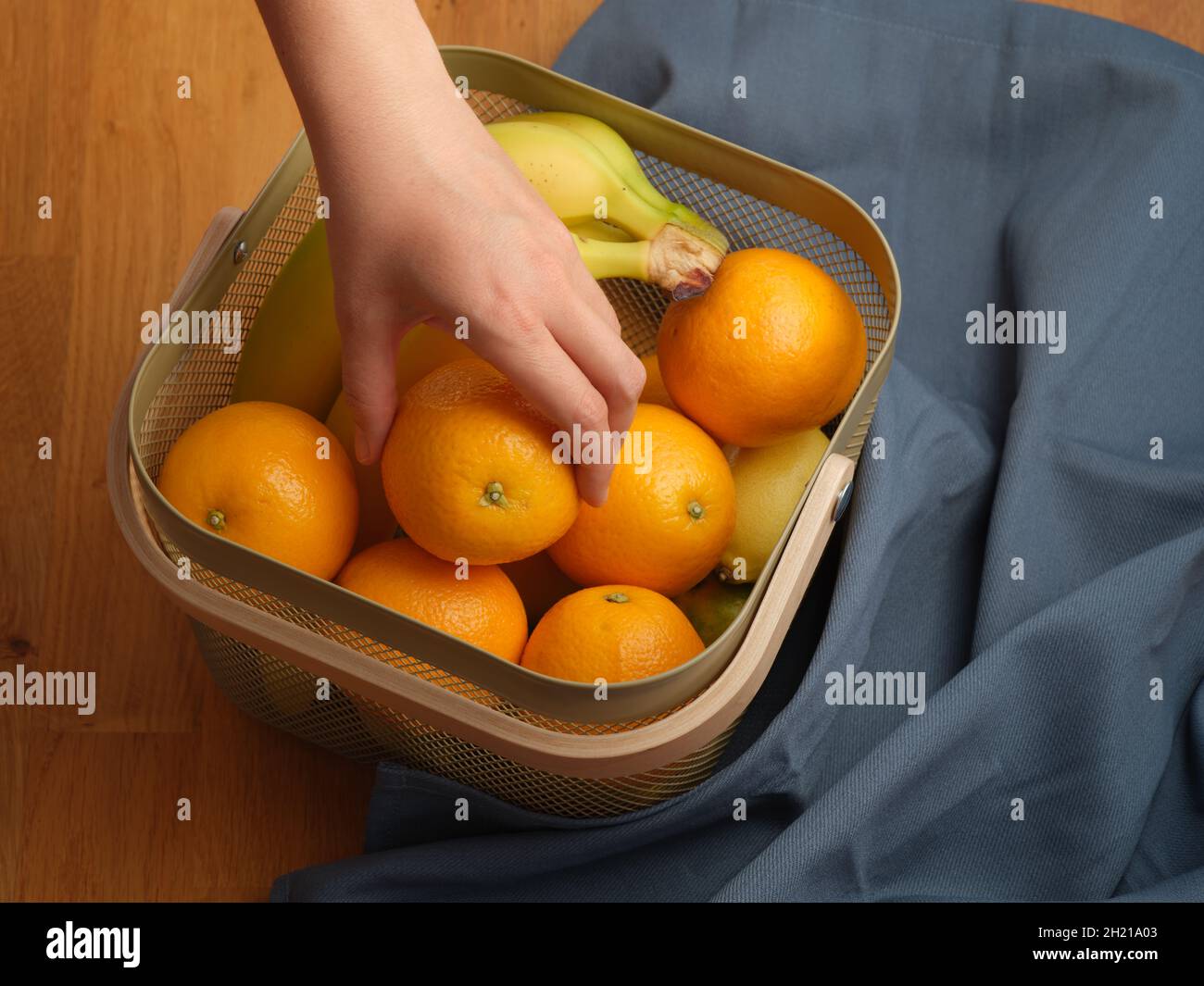 Une femme mettant sa main dans un panier de fruits et tirant une orange.Gros plan. Banque D'Images