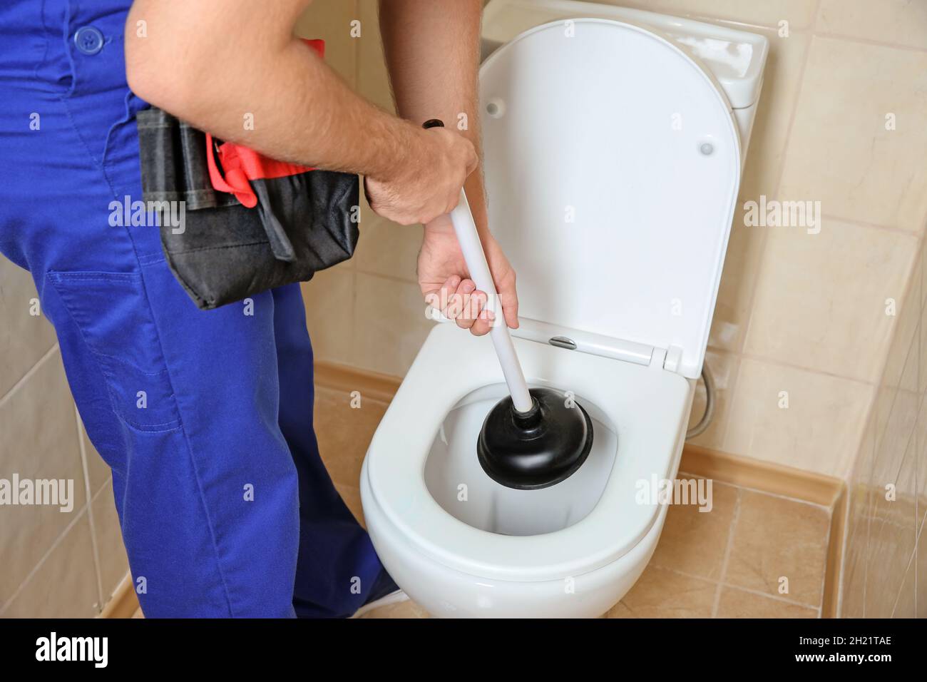 Plomber les toilettes de réparation avec le plongeur manuel à l'intérieur  Photo Stock - Alamy