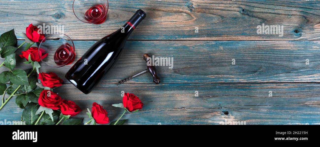 Vacances de Saint Valentin avec roses rouges, bouteille de vin et verres sur des planches de bois bleu pâle Banque D'Images