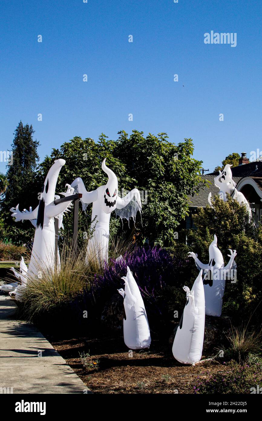 Grand rassemblement d'au moins huit fantômes gonflables soufflés faisant face au trottoir dans une rue résidentielle de la Californie ensoleillée pour la fête d'Halloween Banque D'Images