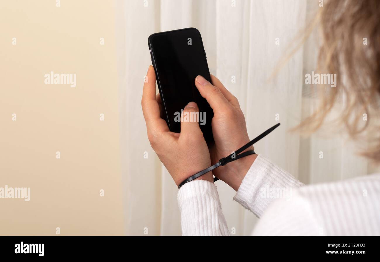 Femme tenant le smartphone avec les mains plactiques menottées. Téléphone mobile addiction concept. Banque D'Images