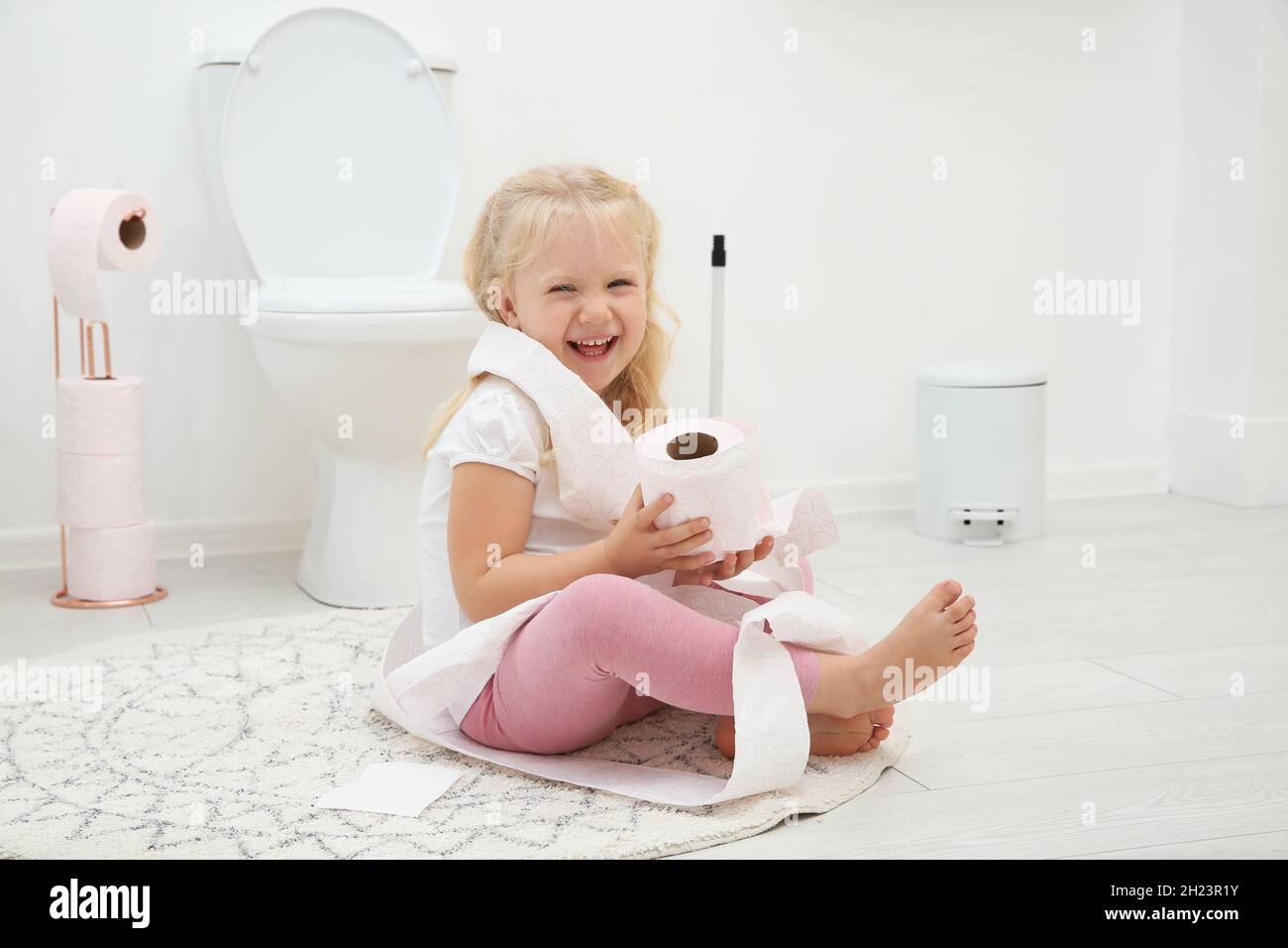 Jolie petite fille jouant avec du papier toilette dans la salle de bains  Photo Stock - Alamy