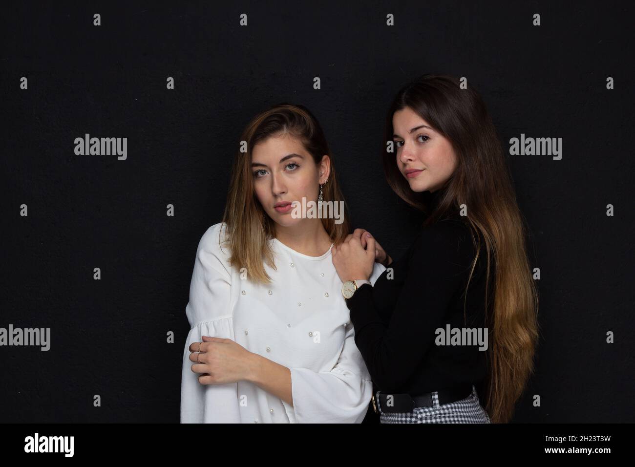Portrait de deux femmes amies avec des gestes d'affection sur fond noir Banque D'Images