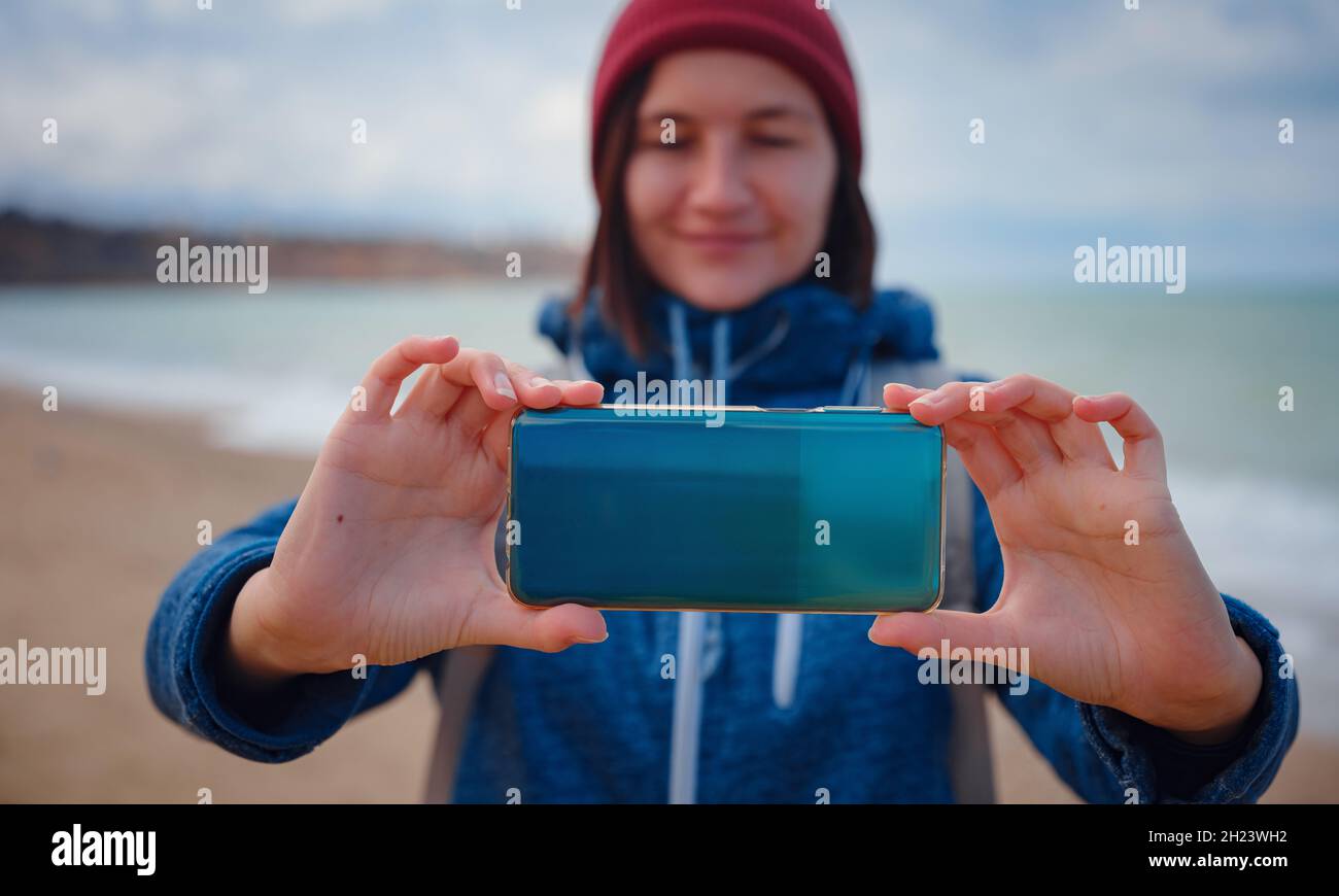 Une femme prend une photo de la mer sur smartphone, la femme voyage le long de la côte en saison froide.Extérieur.POV.Gros plan Banque D'Images