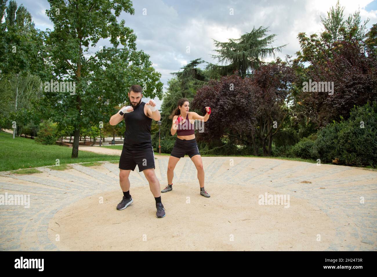 Un jeune caleçon caucasien, homme et femme, entraîne la boxe dans un parc Banque D'Images