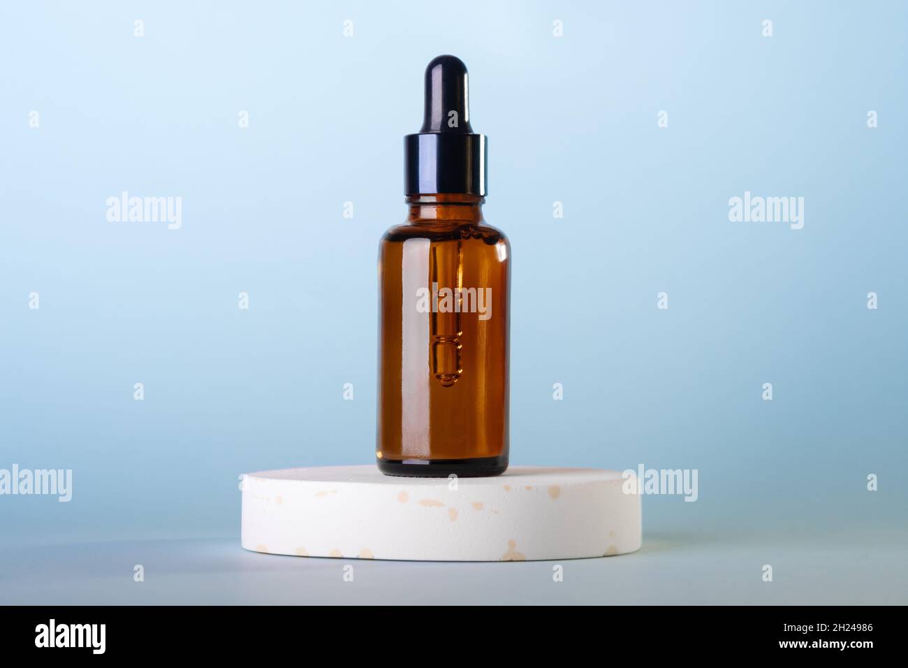 Flacons à cosmétiques compte-gouttes en verre ambré, podium blanc sur fond bleu pastel.Scène avec des formes géométriques.Vitrine. Banque D'Images