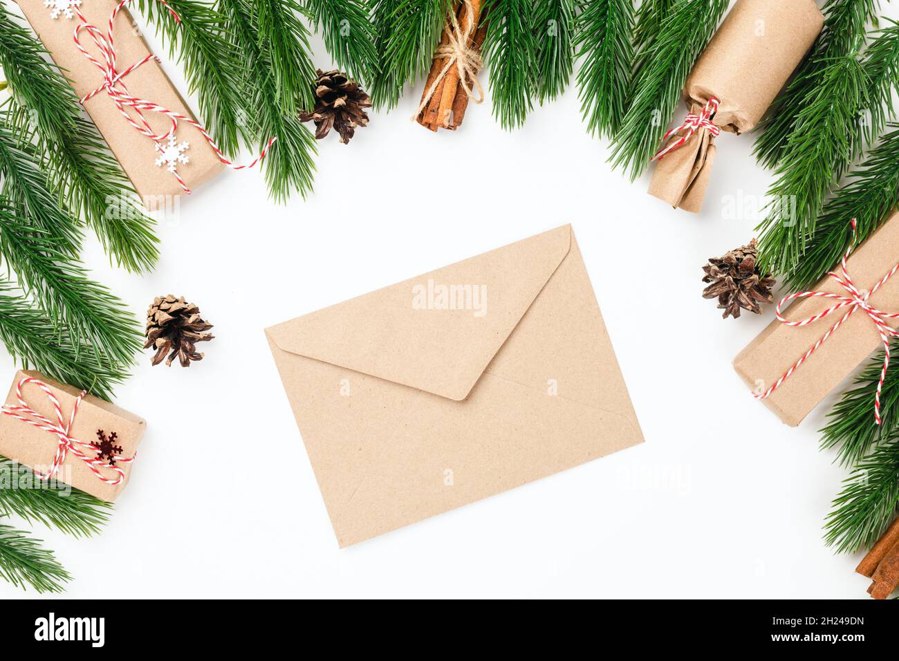 Fond de noël de l'enveloppe vierge artisanale pour la lettre au Père Noël dans le cadre de branches d'arbre de Noël avec des décorations Banque D'Images